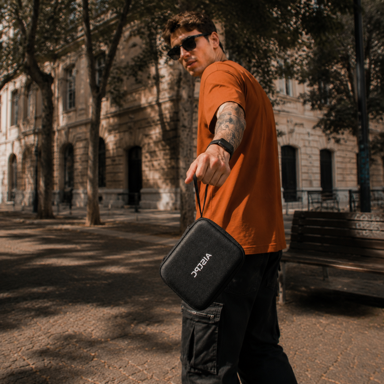AISLPC portable carrying case lifestyle blog cover showing a man holding a black travel storage bag outdoors.