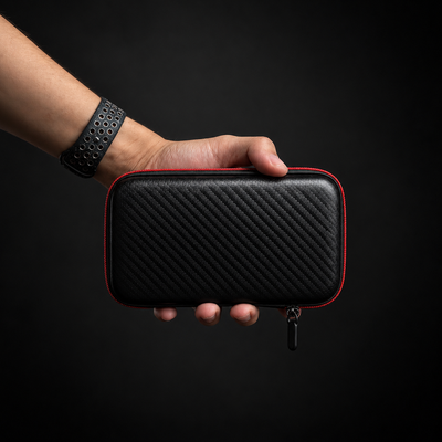 AISLPC GuardShell carrying case held in hand, featuring a black carbon fiber texture, red trim, and zipper design for protecting retro gaming handheld consoles.